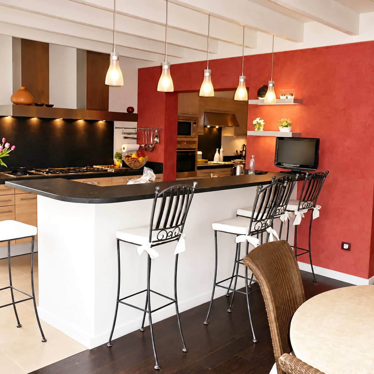 Cuisine ouverte contemporaine avec un bar arrondi blanc et noir, des tabourets en fer forgé, des suspensions et un mur rouge patiné.