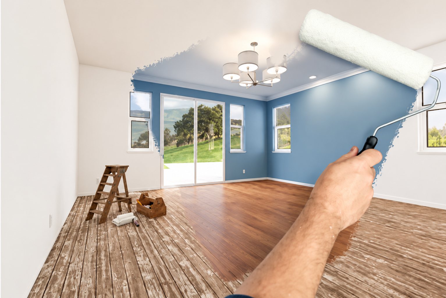 Une main tient un rouleau de peinture blanche qui révèle une pièce rénovée aux murs bleus et au parquet brillant, tandis que l'autre moitié montre un sol abîmé et un escabeau.