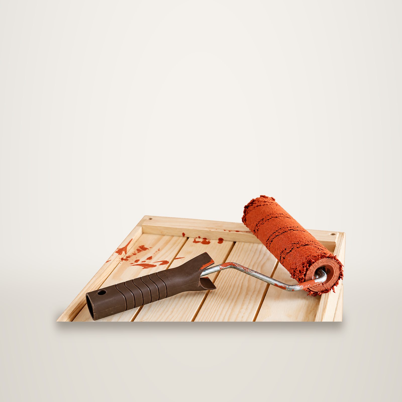 Rouleau de peinture terracotta posé dans une caisse en bois, sur fond de studio uni.