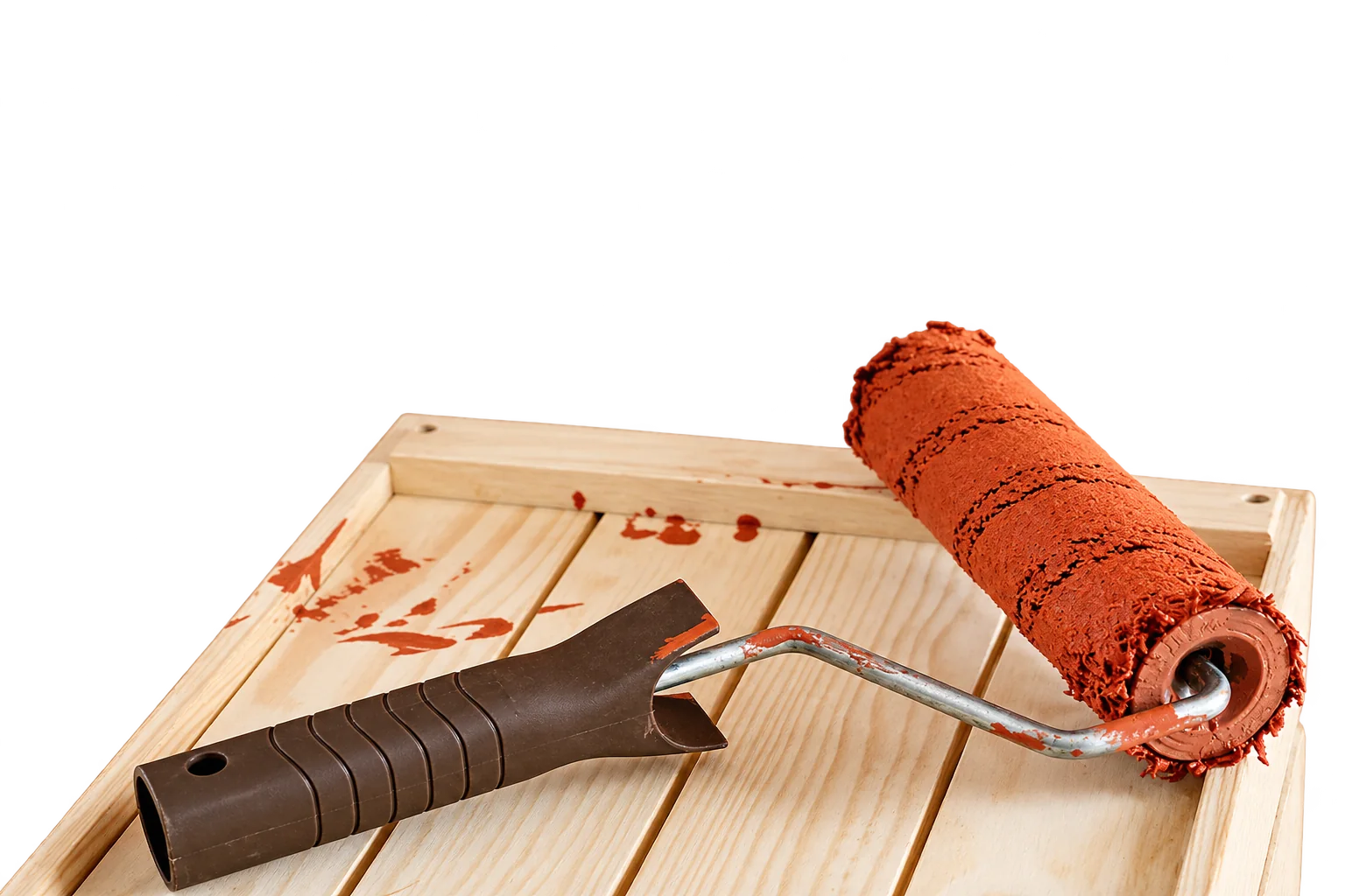 Un rouleau à peinture imbibé de peinture terracotta repose sur une caisse en bois clair devant un mur de même couleur.